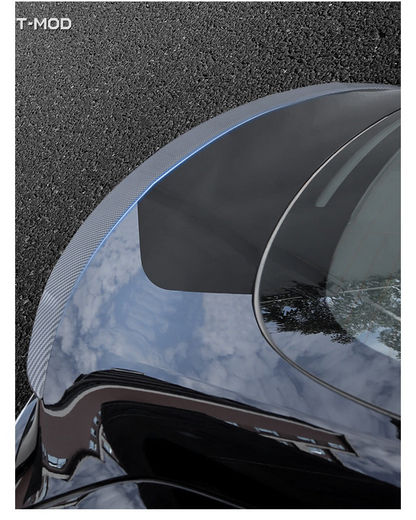 Top view of a carbon-fiber-textured performance-style spoiler installed on a Tesla