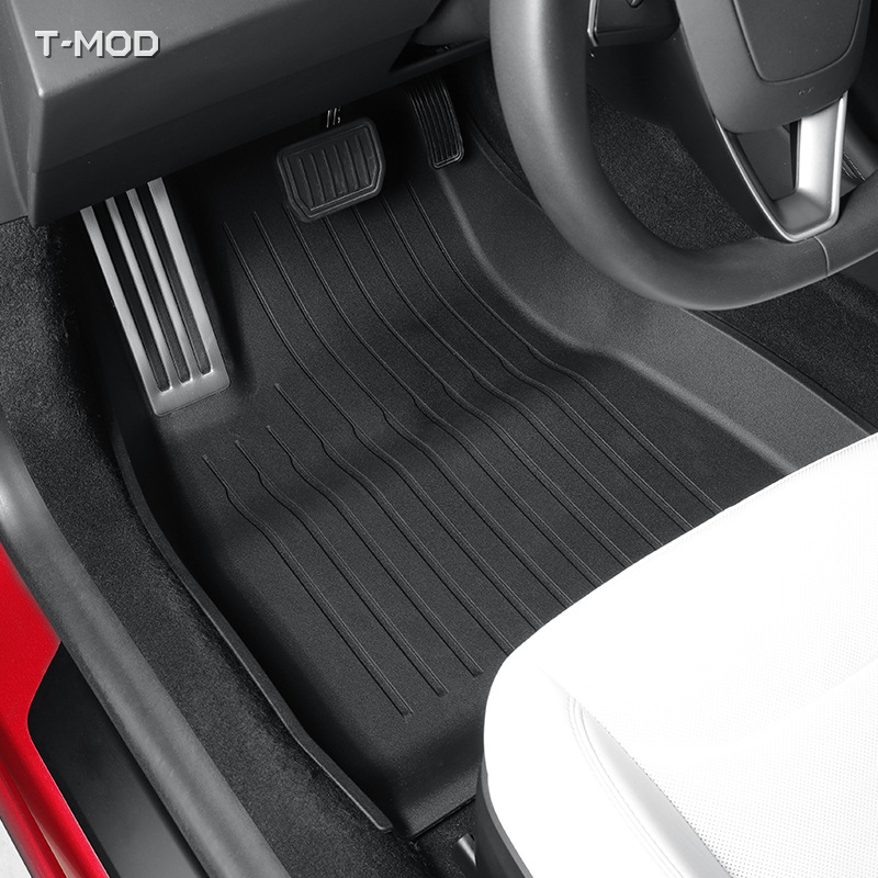 Driver-side black floor mat with silver aluminum pedal plate in a Tesla Model 3 Highland